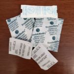 a pile of silica gel packets sitting on top of a wooden table