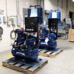 two blue air compressors are sitting on wooden pallets in a room