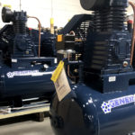 several blue general air compressors are lined up in a warehouse
