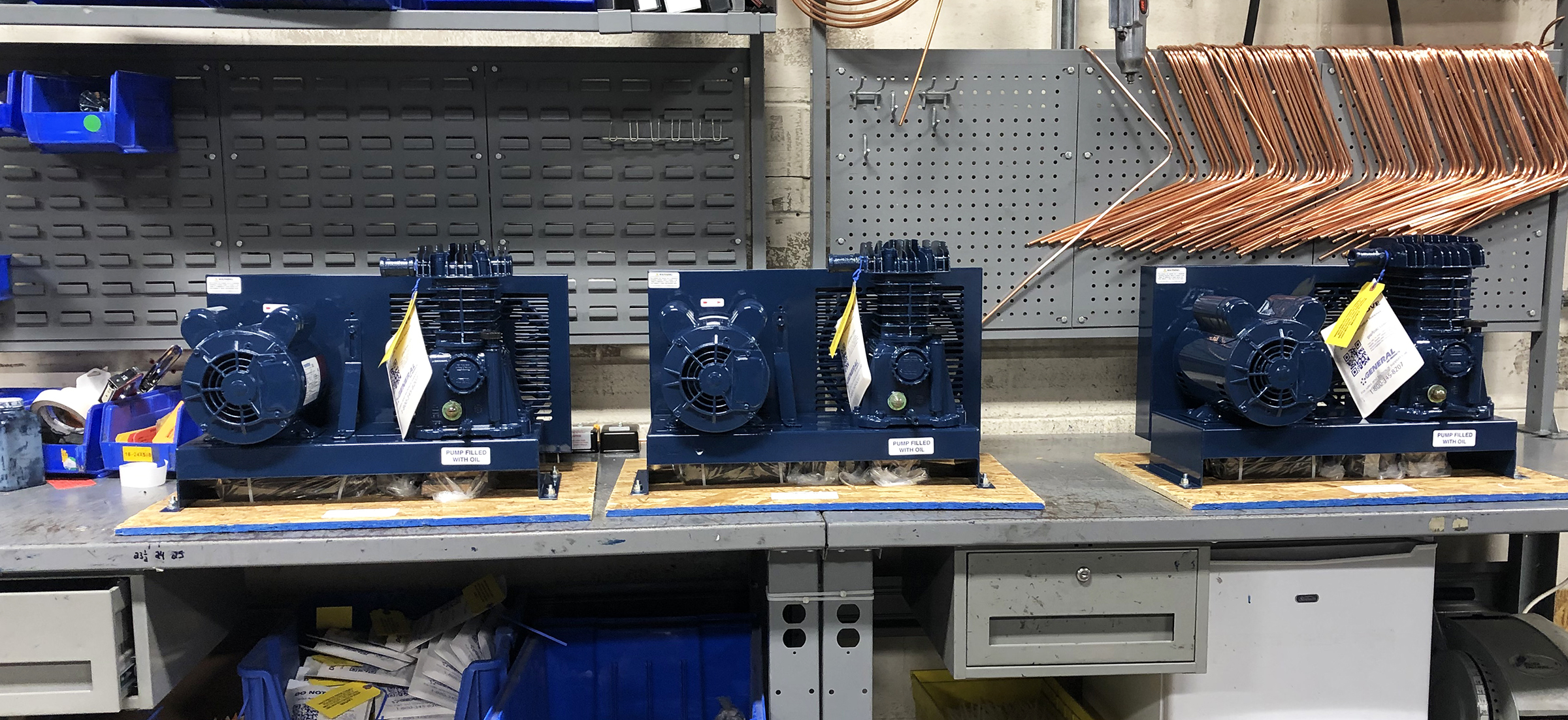 three blue compressors are lined up on a workbench