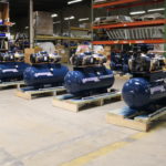 several blue air compressors are lined up in a warehouse