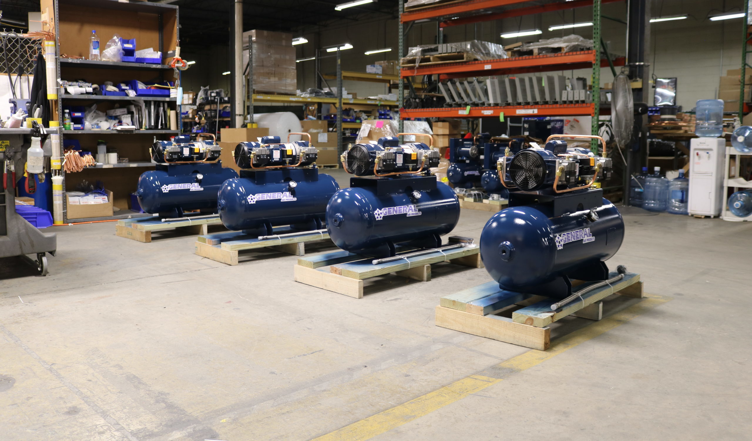 several blue air compressors are lined up in a warehouse