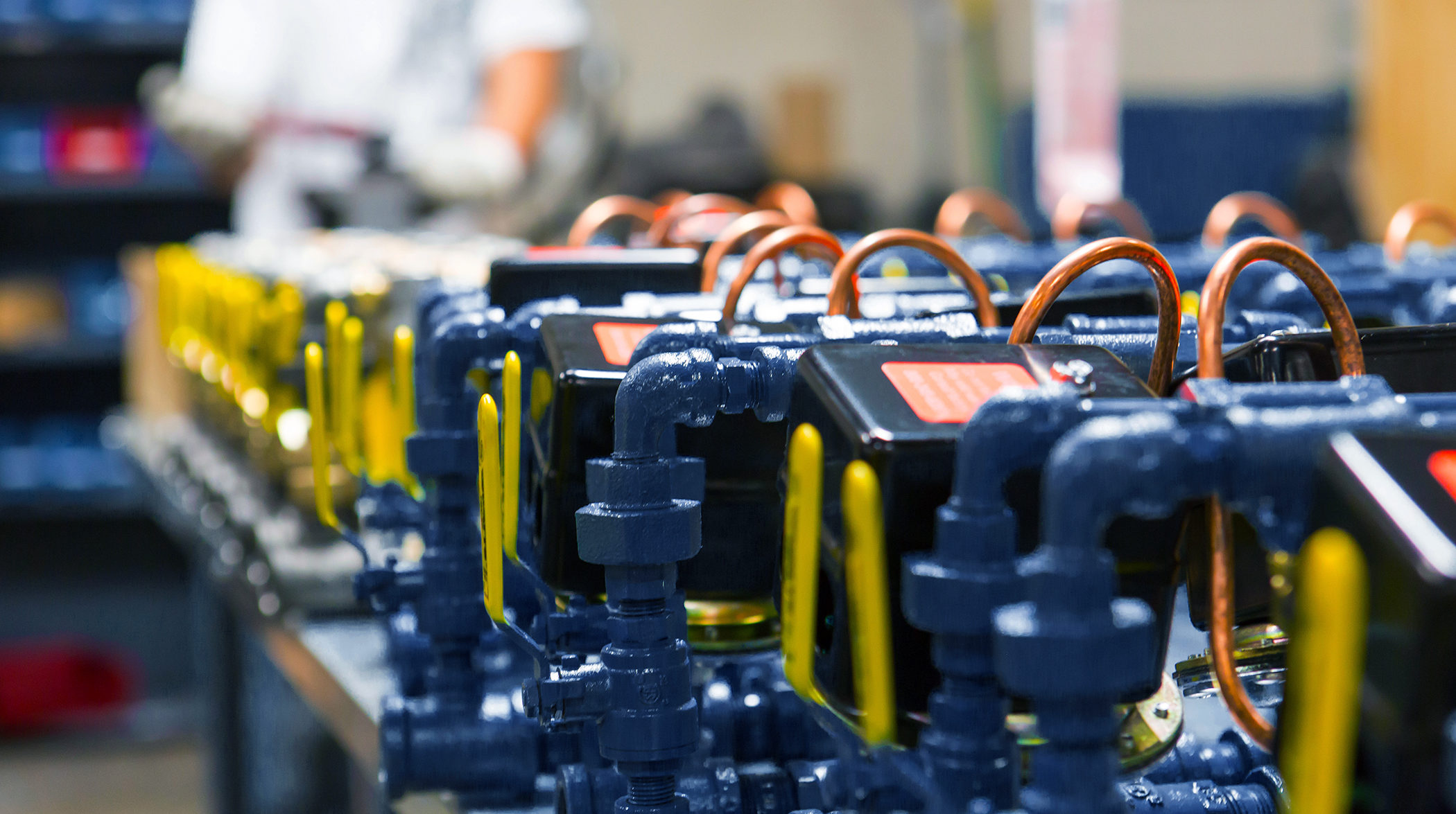 a row of blue and yellow valves with a red label that says ' warning ' on it