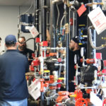 a man in a blue hat stands in front of a bunch of pipes