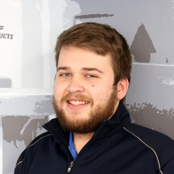 a man with a beard is smiling in front of a sign that says products