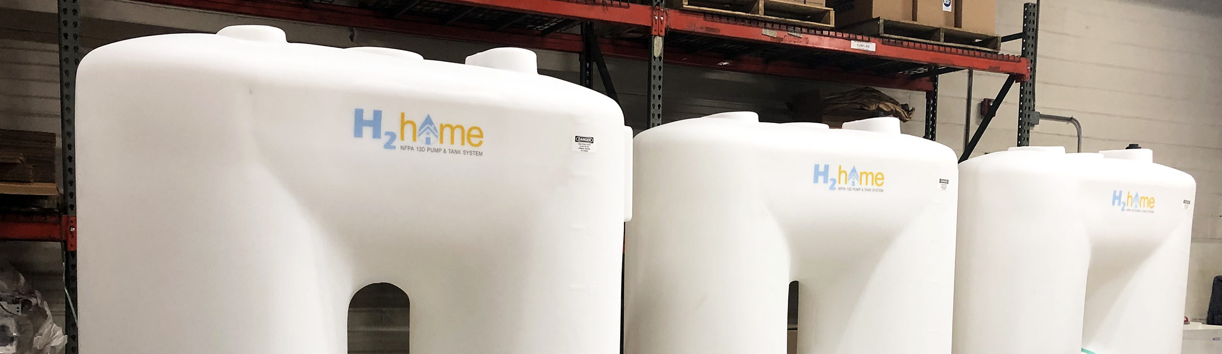 a row of white h-home tanks are lined up in a warehouse